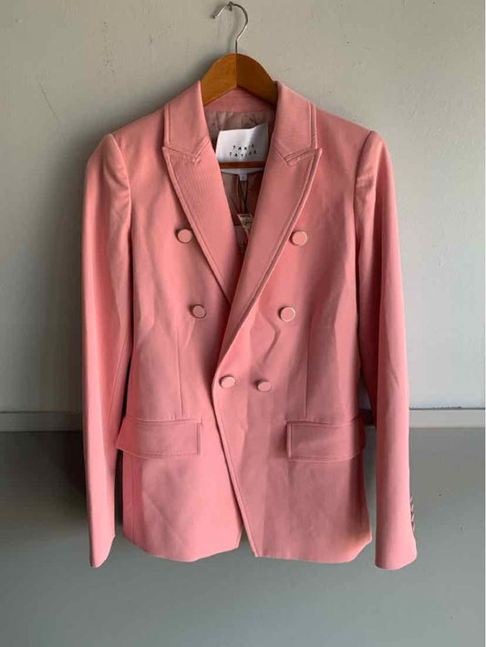Pink double-breasted blazer with notch lapels and front flap pockets hanging on wooden hanger.