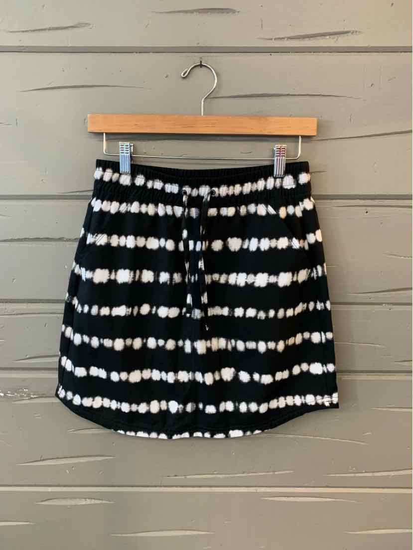Black mini skirt with white horizontal tie-dye stripes hanging on wooden hanger.
