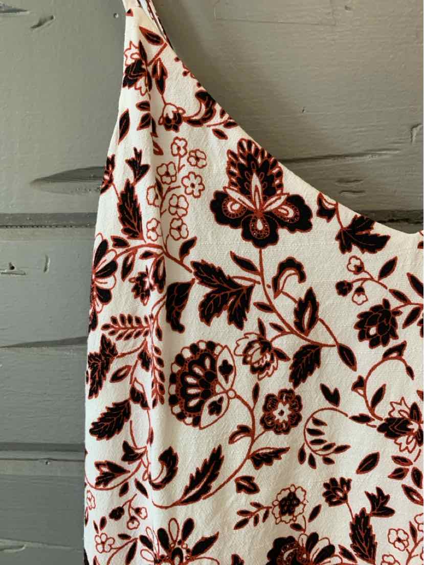 White sleeveless top with red and black floral print and scoop neckline.