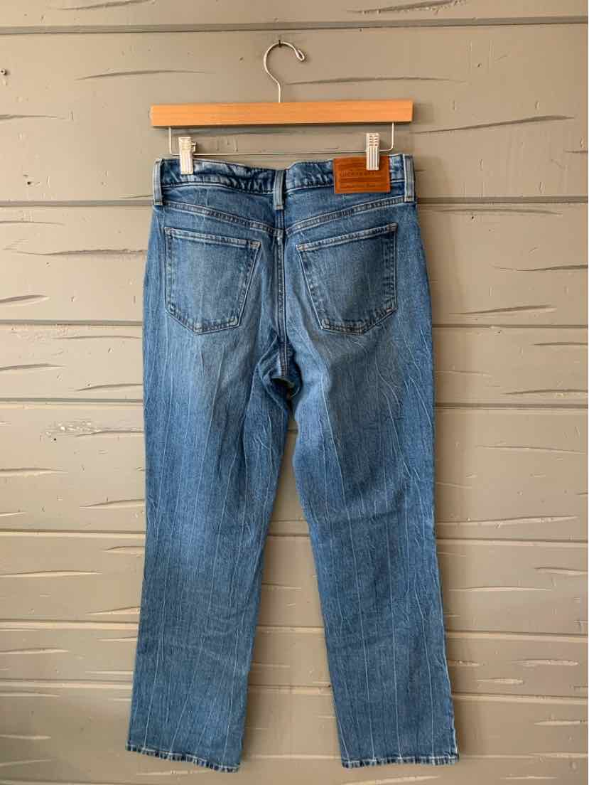 Light wash blue denim jeans with straight leg cut, two back pockets, and a brown leather brand patch on the waistband.