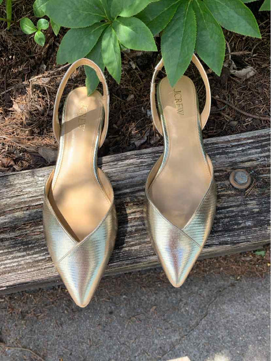 Pair of metallic gold pointed-toe slingback flats with low heels and smooth leather finish.