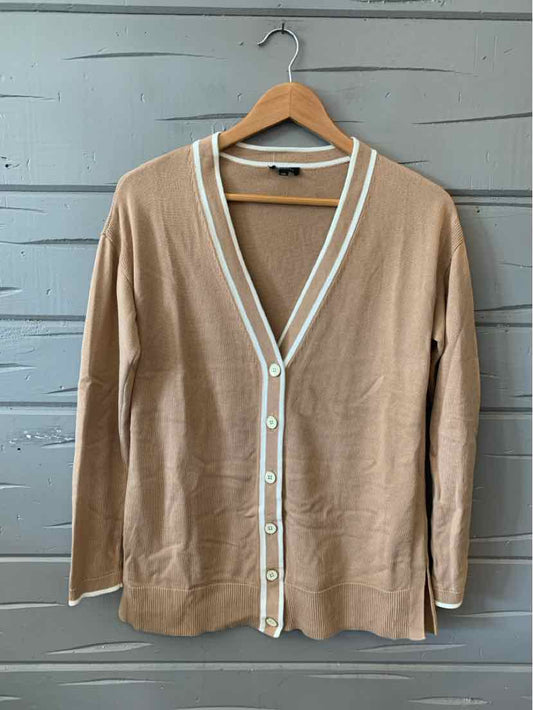 Tan long-sleeve cardigan with white trim and button-down front in size XS on wooden hanger.