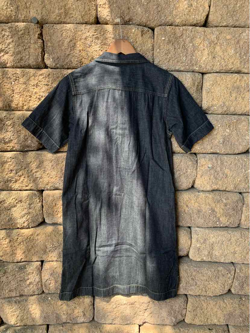 Black short-sleeve denim dress with collar and back yoke detail hanging on stone wall.