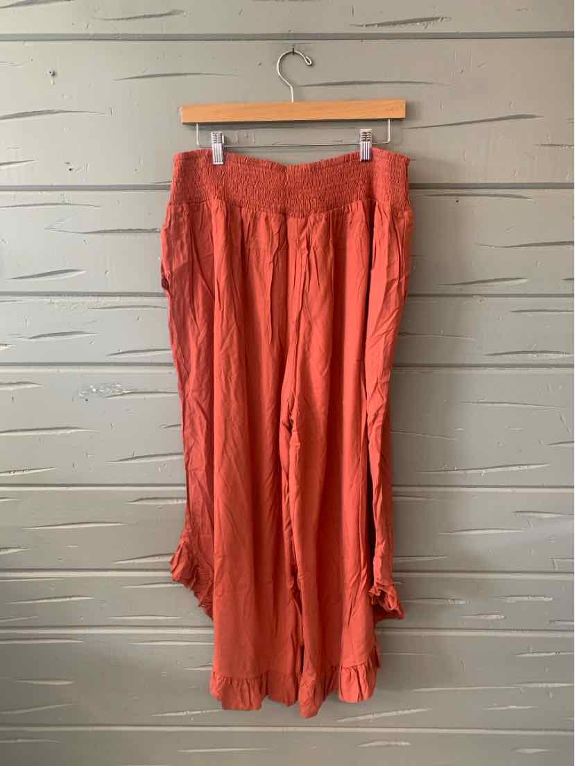 Rust orange wide-leg pants with elastic smocked waistband and ruffled hem detailing.