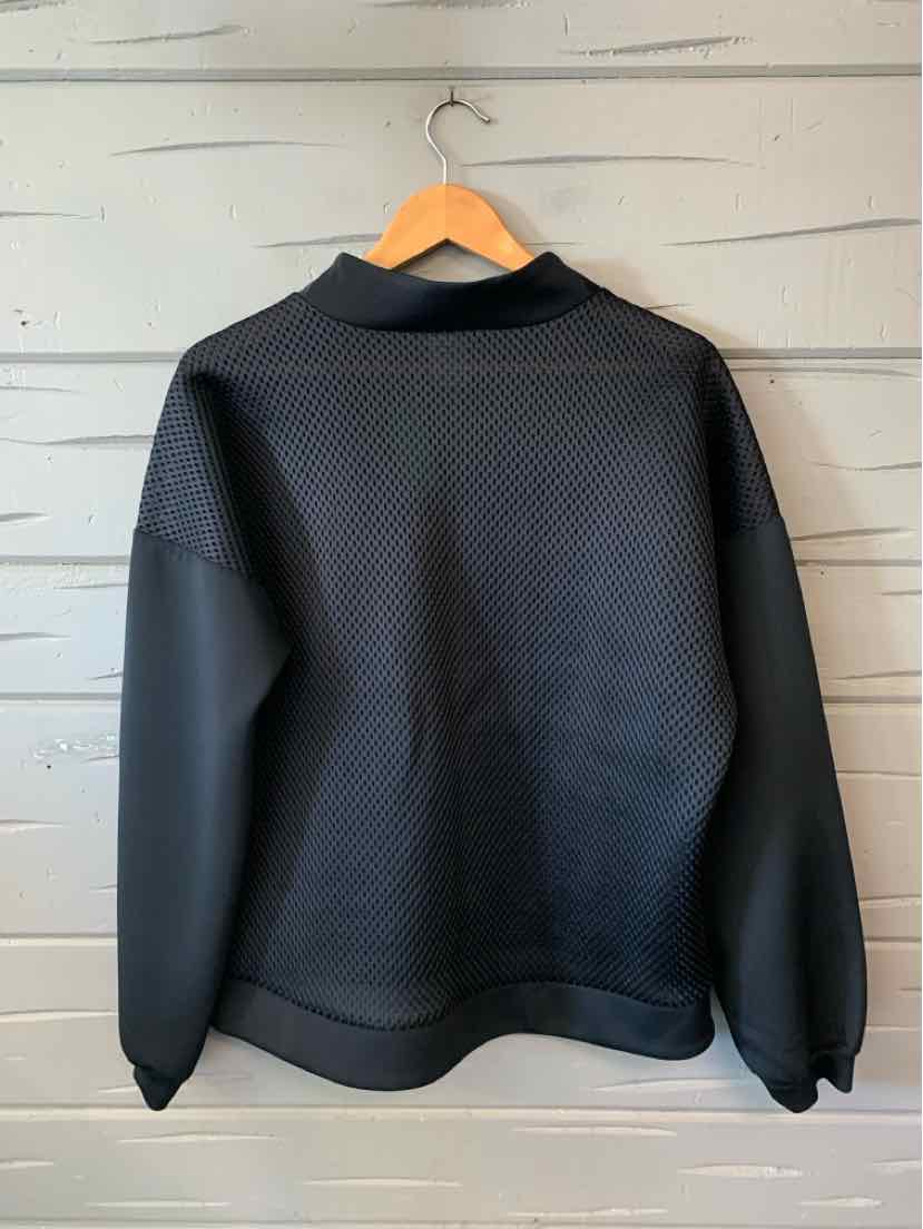 Black long-sleeve pullover with a high neckline and relaxed fit hanging on wooden hanger.