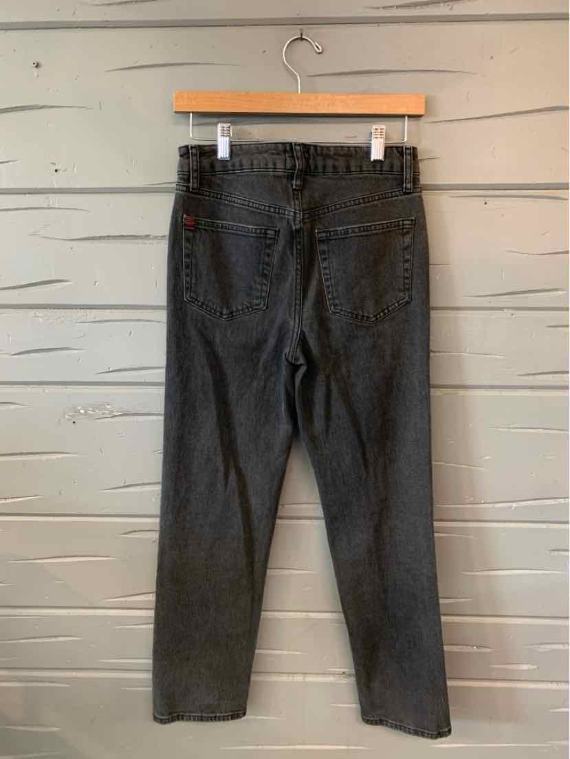Charcoal gray slim-fit jeans with high waist and back pockets hanging on wooden hanger.
