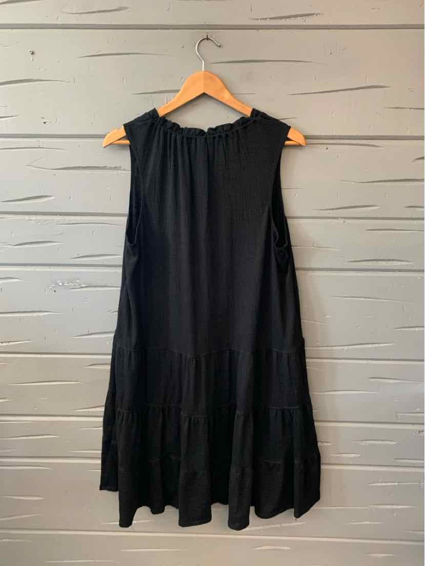 Sleeveless black midi dress with ruffled neckline and tiered hem on wooden hanger.
