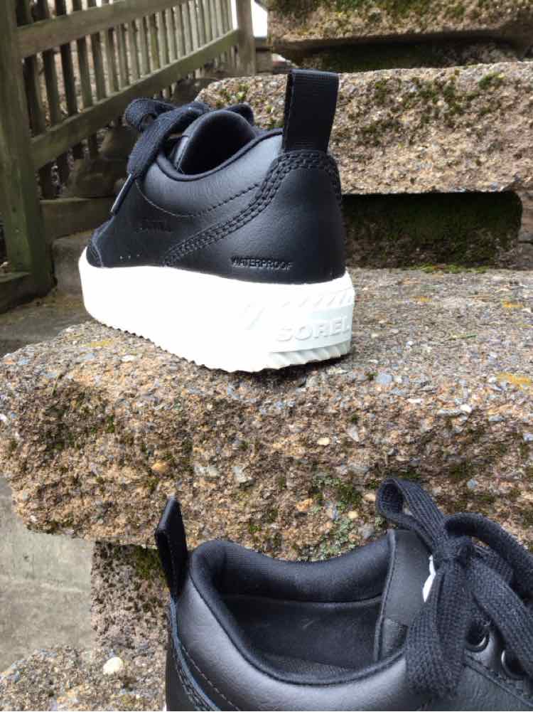 Black leather sneaker with white textured sole, black pull tab, and lace-up design, size 6.