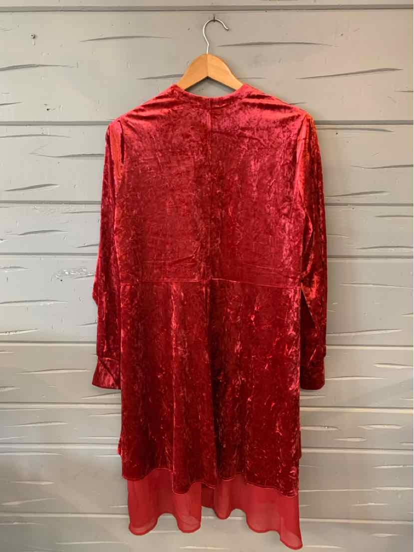 Red velvet long-sleeve tunic with loose fit and layered hem hanging on wooden hanger.