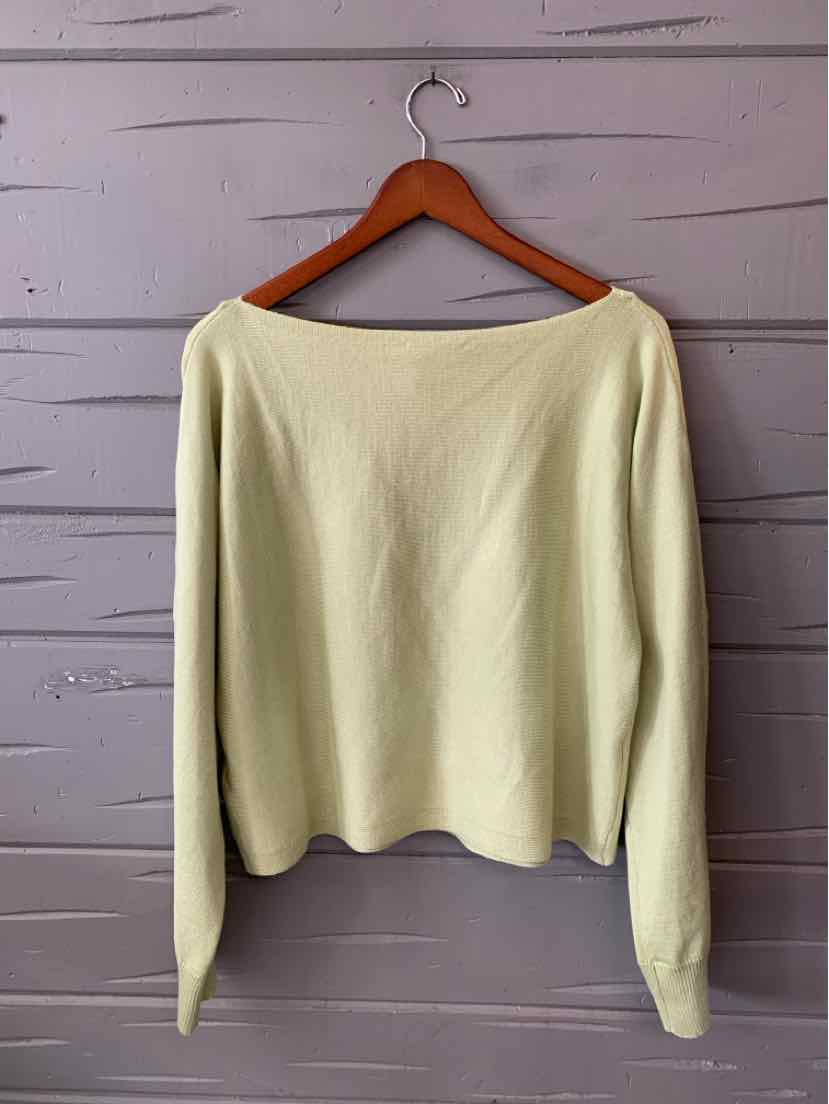 Cream-colored knit sweater with long sleeves and a boat neckline hanging on a wooden hanger.