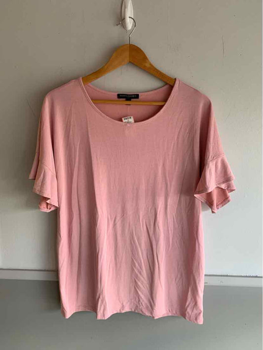 Light pink short-sleeve top with ruffled sleeves and round neckline on wooden hanger.