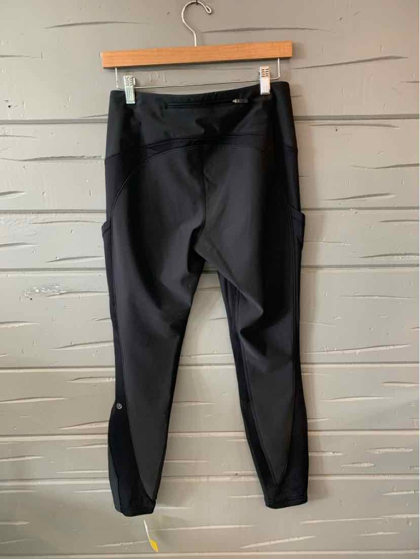 Black high-waisted leggings with a slim fit and ankle-length cut hanging on a wooden hanger.