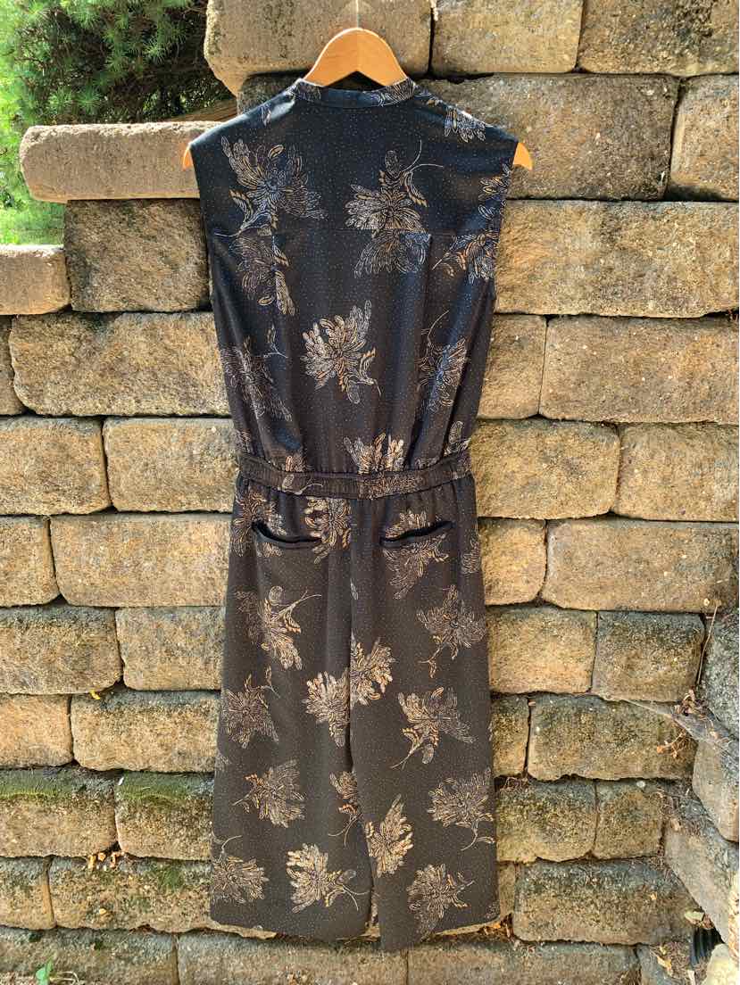 Black sleeveless midi dress with floral pattern and adjustable waist belt hanging on wooden hanger.